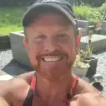 Relaxed man smiling outdoors, enjoying nature during daytime.
